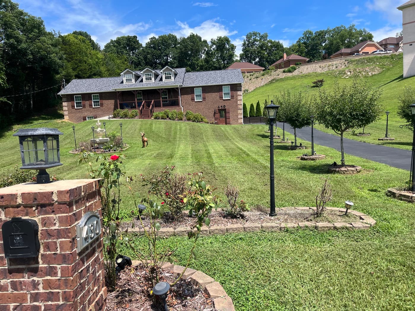 Freshly cut and striped lawn at a large brick home with tidy landscaping beds in East Tennessee
